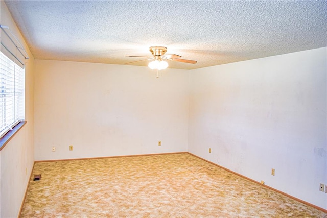 empty room featuring ceiling fan, carpet floors, and a textured ceiling