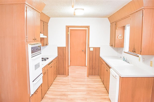 kitchen featuring a textured ceiling, white appliances, light hardwood / wood-style flooring, and sink