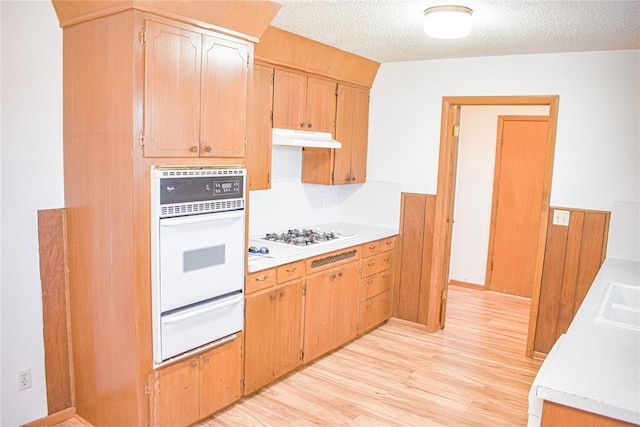 kitchen featuring a textured ceiling, light hardwood / wood-style flooring, white appliances, and sink