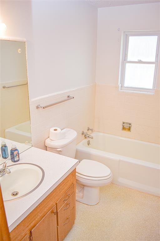 bathroom featuring vanity, a bath, tile walls, and toilet