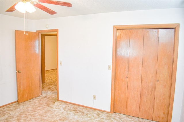 unfurnished bedroom featuring ceiling fan, light carpet, and a closet