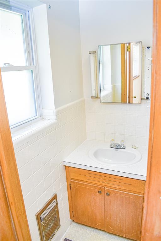 bathroom featuring vanity and tile walls