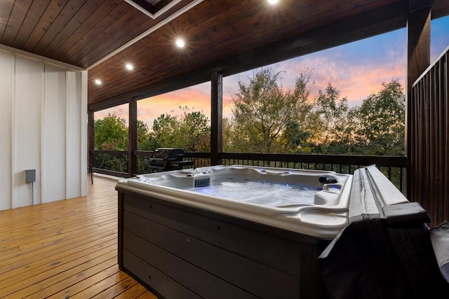 deck at dusk with a hot tub and a grill