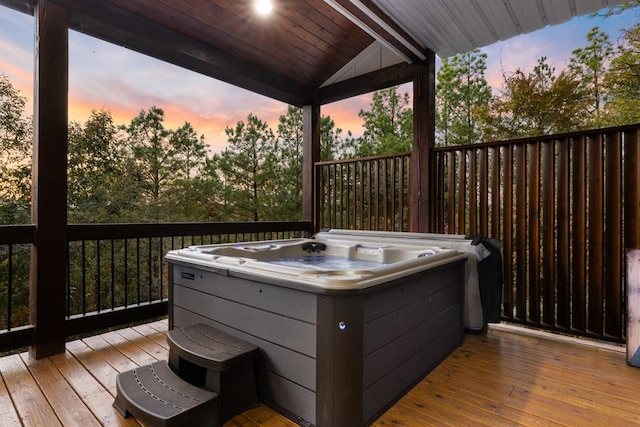 deck at dusk featuring a hot tub