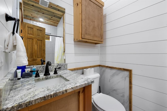 bathroom featuring wooden walls, wood ceiling, and vanity