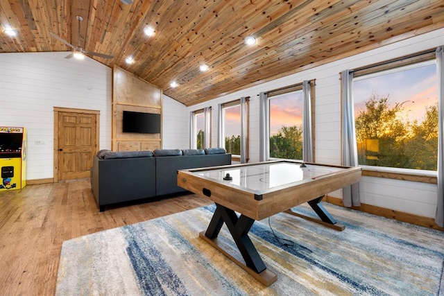 game room with wooden walls, wooden ceiling, ceiling fan, light hardwood / wood-style flooring, and high vaulted ceiling