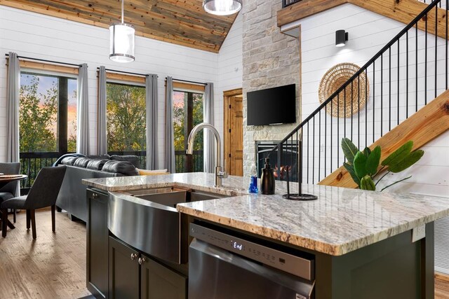 kitchen with light stone counters, dishwasher, light hardwood / wood-style floors, and pendant lighting