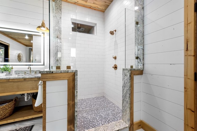 bathroom with wood walls, tiled shower, wooden ceiling, and vanity