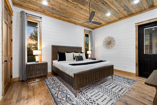 bedroom featuring wood walls, wood ceiling, multiple windows, ceiling fan, and wood-type flooring