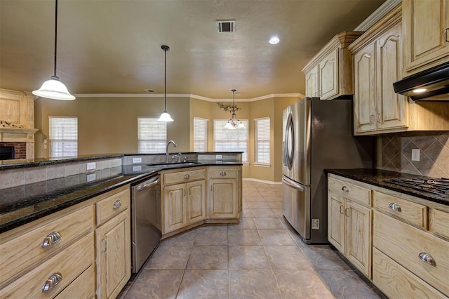 kitchen with sink, dark stone countertops, light brown cabinetry, decorative light fixtures, and stainless steel appliances