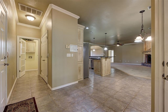 kitchen featuring a center island with sink, ceiling fan with notable chandelier, crown molding, a fireplace, and decorative light fixtures