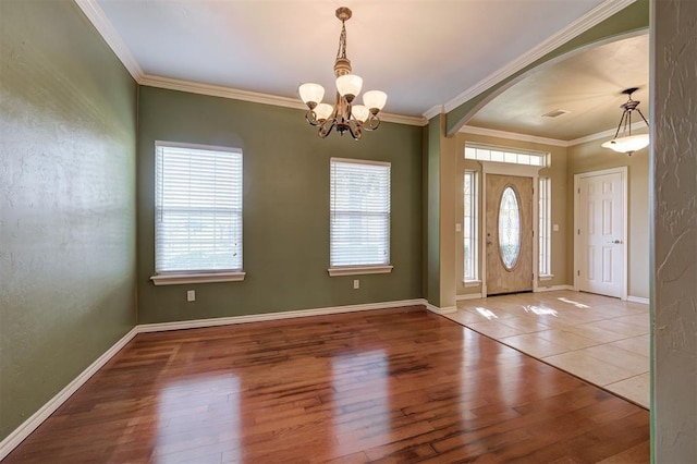 entrance foyer featuring hardwood / wood-style flooring, a notable chandelier, and ornamental molding