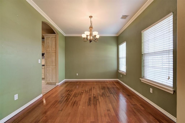 spare room with a chandelier, wood-type flooring, and crown molding