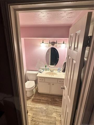 bathroom featuring toilet, vanity, a textured ceiling, and hardwood / wood-style flooring