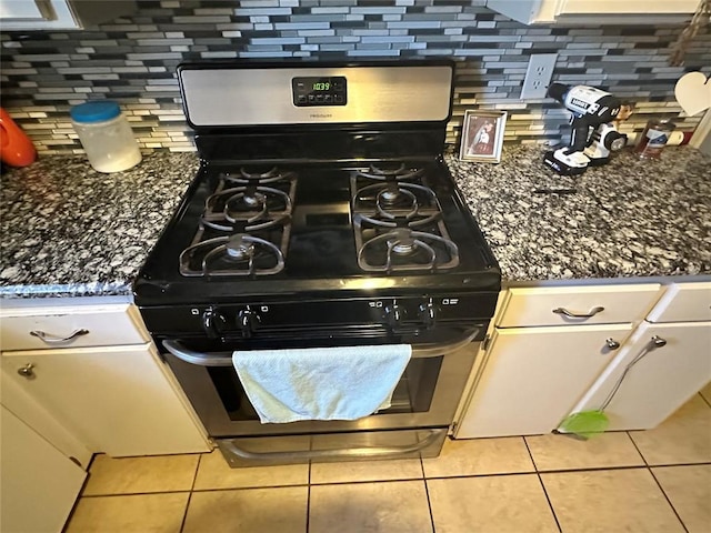 interior details with dark stone countertops, backsplash, and gas range