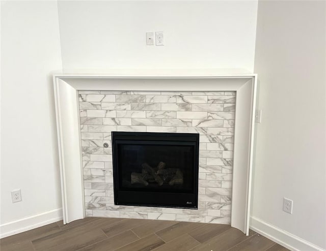 details featuring wood tiled floor, a glass covered fireplace, and baseboards