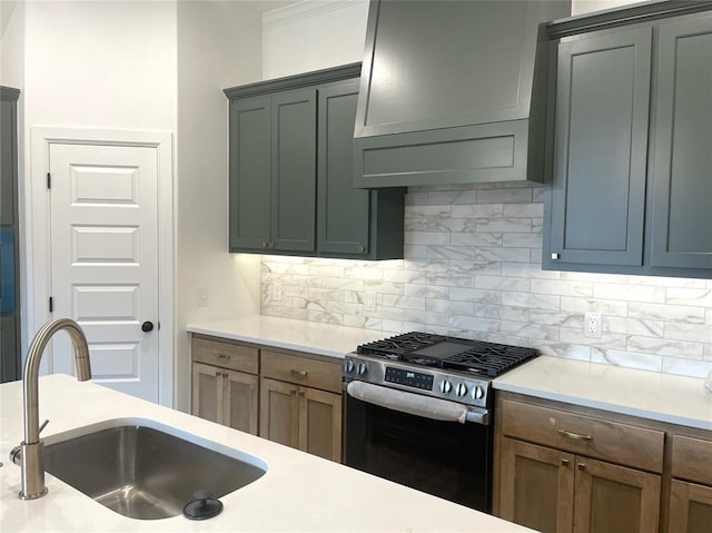 kitchen with light countertops, brown cabinetry, a sink, and gas stove