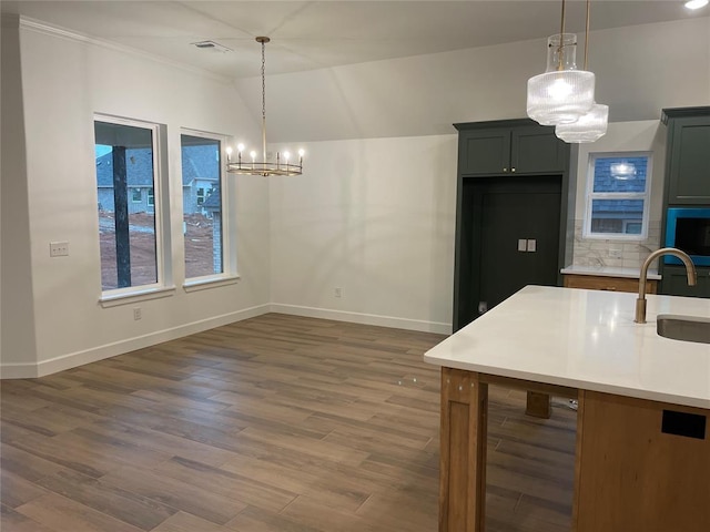 kitchen featuring dark wood finished floors, light countertops, a sink, and decorative light fixtures