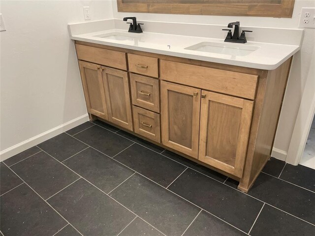 full bath featuring double vanity, baseboards, a sink, and tile patterned floors