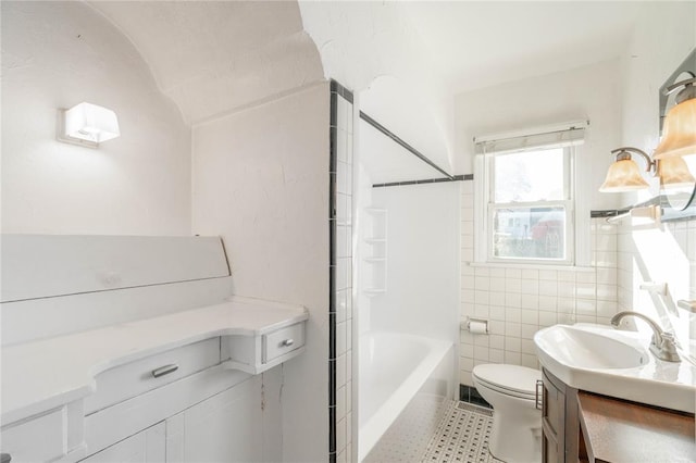 full bathroom with toilet, vanity, tile walls, and  shower combination