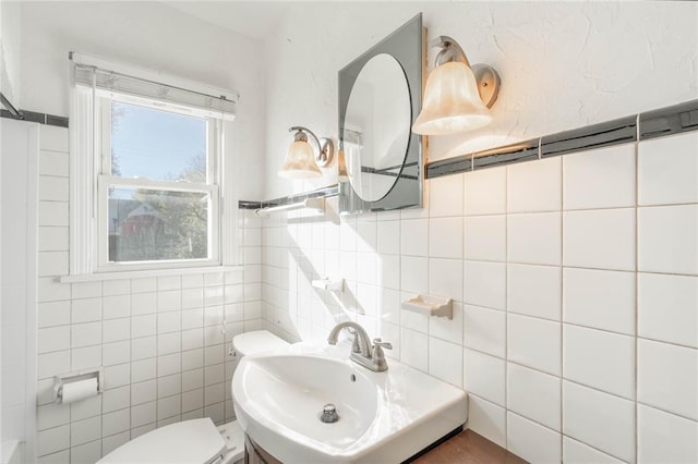 bathroom with toilet, tile walls, and sink