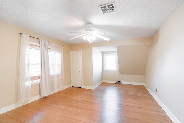 additional living space featuring a textured ceiling, ceiling fan, and light hardwood / wood-style flooring