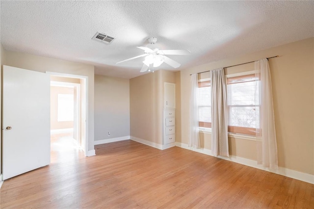 spare room with ceiling fan, a textured ceiling, and light wood-type flooring