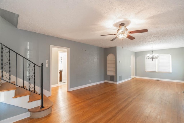 unfurnished living room featuring wood-type flooring, ceiling fan with notable chandelier, and a textured ceiling