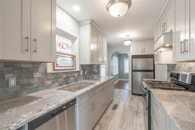 kitchen featuring white cabinetry, appliances with stainless steel finishes, tasteful backsplash, light stone counters, and sink