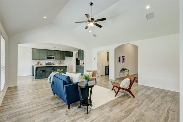 living room with high vaulted ceiling, light hardwood / wood-style flooring, and ceiling fan