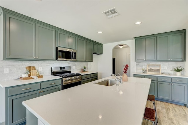 kitchen with light wood-type flooring, tasteful backsplash, a breakfast bar, stainless steel appliances, and sink