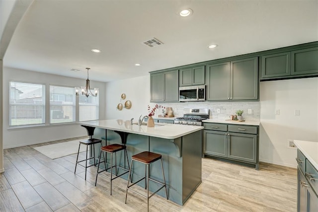 kitchen featuring sink, an island with sink, appliances with stainless steel finishes, and light hardwood / wood-style flooring