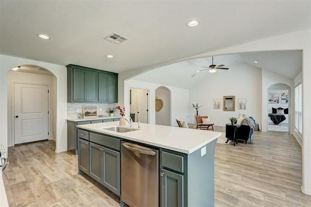 kitchen with stainless steel dishwasher, vaulted ceiling, ceiling fan, sink, and a center island with sink