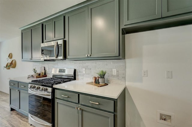 kitchen with backsplash, stainless steel appliances, light hardwood / wood-style flooring, and green cabinets