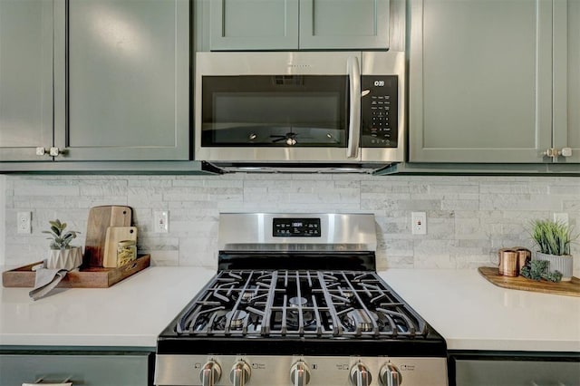 kitchen featuring backsplash, stainless steel appliances, and green cabinetry