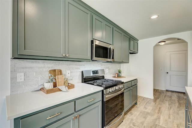 kitchen with decorative backsplash, stainless steel appliances, light hardwood / wood-style flooring, and green cabinets