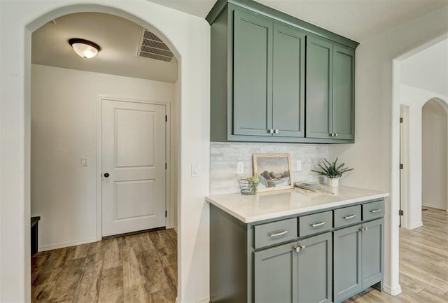 interior space featuring light hardwood / wood-style floors, backsplash, and green cabinetry