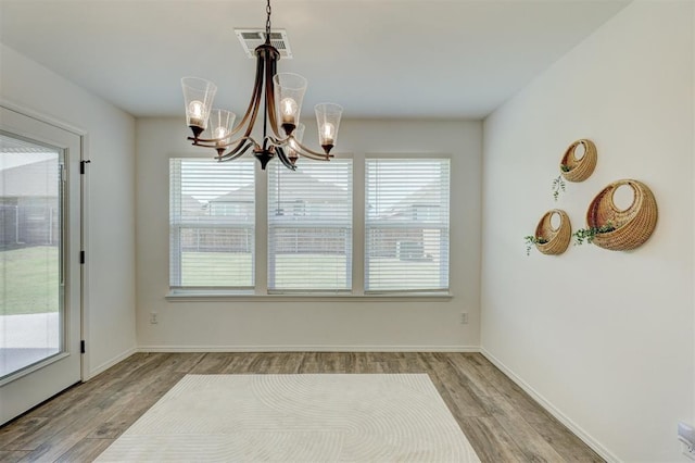 unfurnished dining area featuring plenty of natural light, light wood-type flooring, and an inviting chandelier