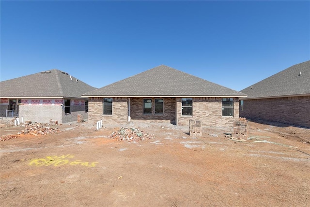 back of house with a shingled roof and brick siding