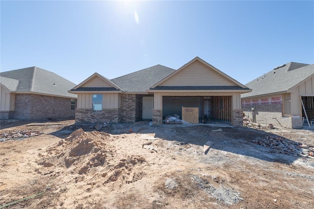 view of front of property with an attached garage, a shingled roof, board and batten siding, and brick siding