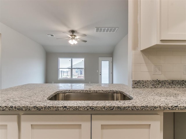 kitchen with ceiling fan, decorative backsplash, visible vents, and light stone countertops