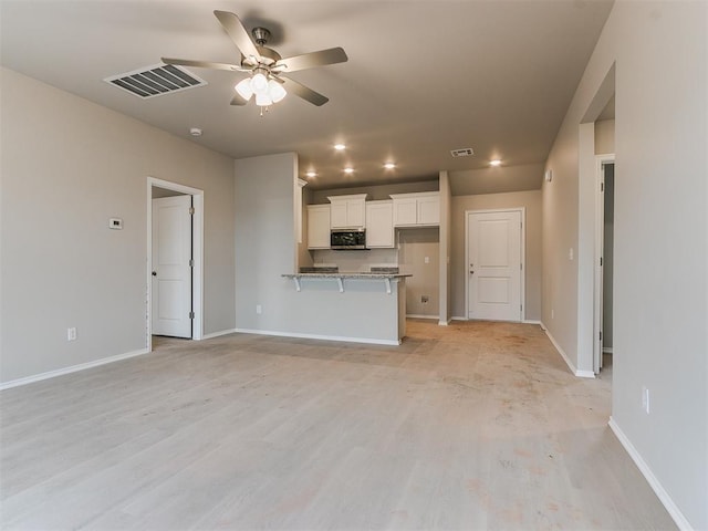 unfurnished living room with light wood-type flooring, baseboards, visible vents, and a ceiling fan