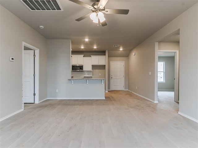 kitchen featuring white cabinetry, visible vents, stainless steel microwave, and ceiling fan