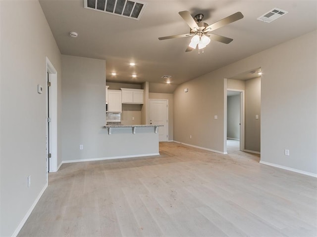 unfurnished living room featuring light wood finished floors, baseboards, visible vents, and ceiling fan