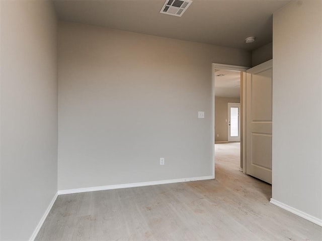 unfurnished room with baseboards, visible vents, and wood finished floors