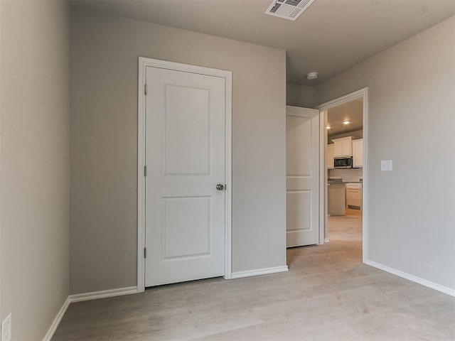 unfurnished bedroom featuring light wood finished floors, baseboards, and visible vents