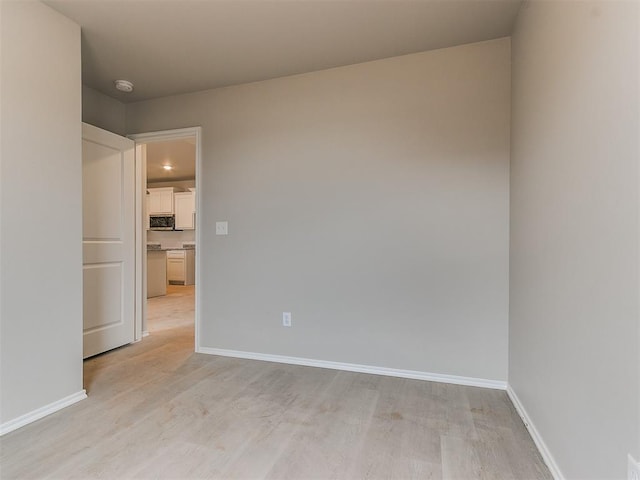 spare room with light wood-style floors and baseboards