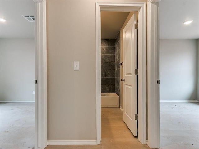 hall with light wood-style floors, recessed lighting, visible vents, and baseboards