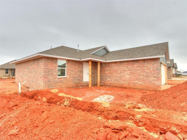 single story home with a garage, a shingled roof, and brick siding