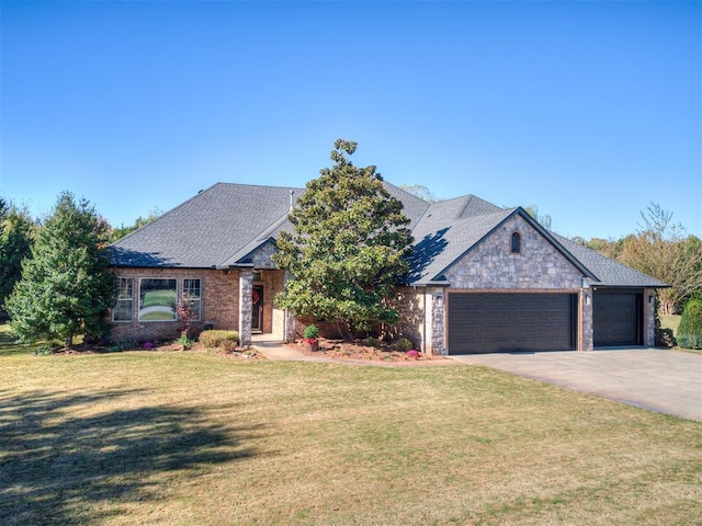 view of front of home with an attached garage, a shingled roof, concrete driveway, stone siding, and a front yard